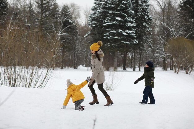 Happy family playing and laughing in winter outdoors in the snow. City park winter day.