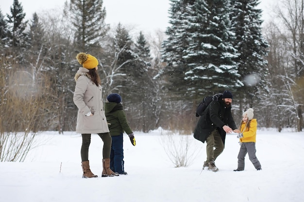 Famiglia felice che gioca e ride in inverno all'aperto nella neve. giornata invernale del parco cittadino.