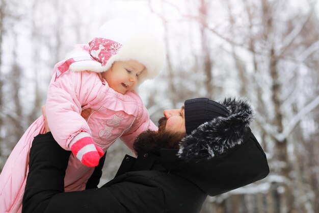 Happy family playing and laughing in winter outdoors in the snow. City park winter day.