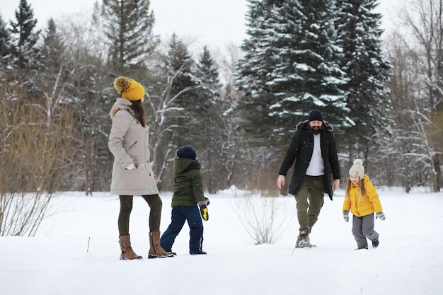 Happy family playing and laughing in winter outdoors in the snow. City park winter day.