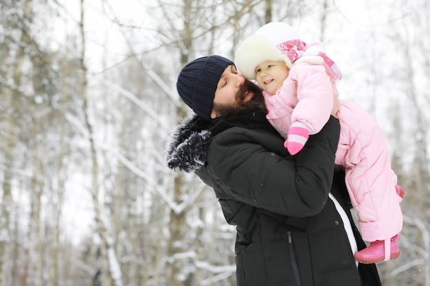 Happy family playing and laughing in winter outdoors in the snow. City park winter day.