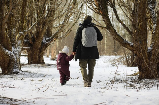 雪の中で屋外で冬に遊んで笑って幸せな家族。シティパークの冬の日。