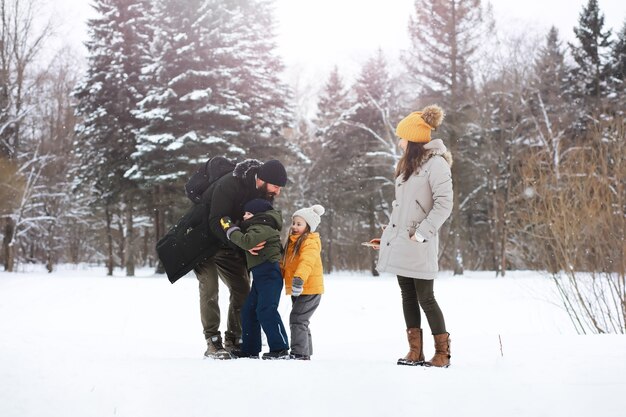 Happy family playing and laughing in winter outdoors in the snow. City park winter day.