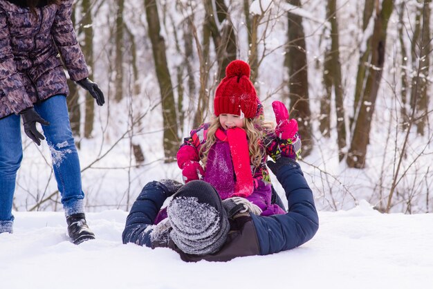 Happy family playing with snow in winter forest