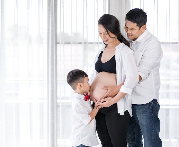 Happy family, pregnant mother, father and son kissing