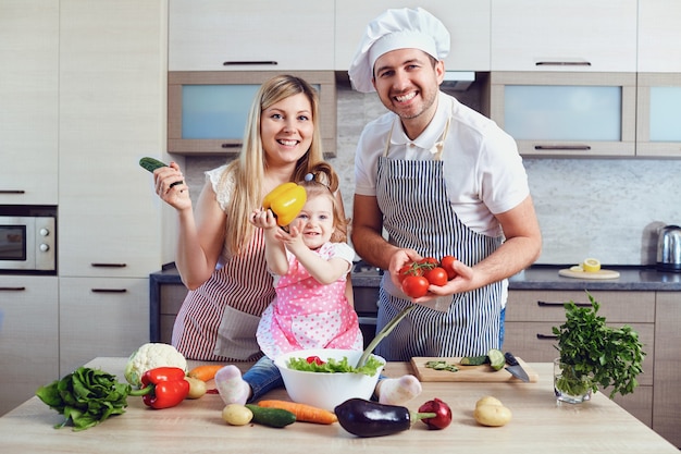 A happy family prepares food in the kitchen