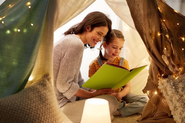 happy family reading book in kids tent at home