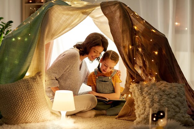 Photo happy family reading book in kids tent at home