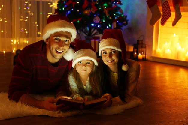 happy family reading book in living room decorated for christmas