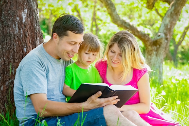 Happy family reading a book on the nature of the Bible