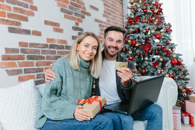 Happy family received confirmation of credit and money on bank account, on credit card, rejoice at home sitting on sofa during New Year and Christmas holidays