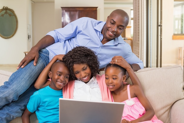 Happy family relaxing on the couch using laptop