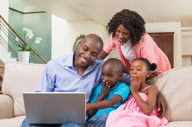 Happy family relaxing on the couch using laptop