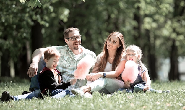 Happy family resting on the lawn in the city Park