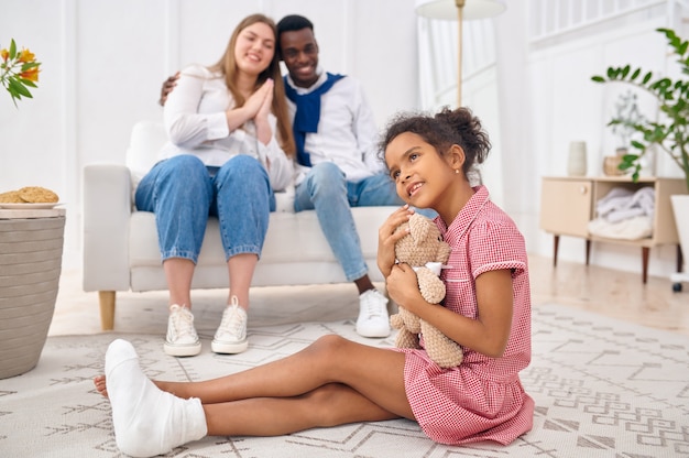 Happy family resting in living room. Mother, father and their daughter poses at home together, good relationship. Mom, dad and female child