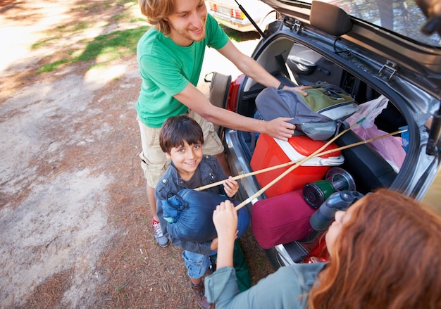 Photo happy family road trip and packing car trunk for camping holiday or vacation above in nature outdoors top view of dad or kids getting ready for travel camp adventure or getaway together in forest