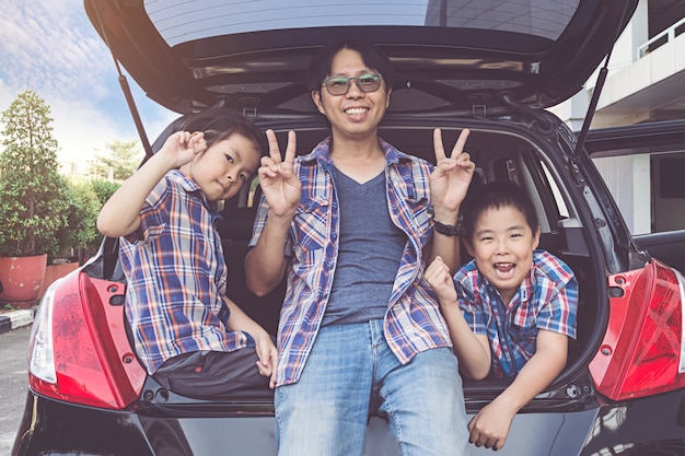 Famiglia felice in viaggio, seduti nel bagagliaio della macchina