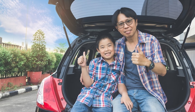 Famiglia felice in viaggio, seduti nel bagagliaio della macchina