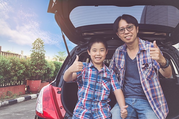 Photo happy family on a road trip, sitting in trunk of car