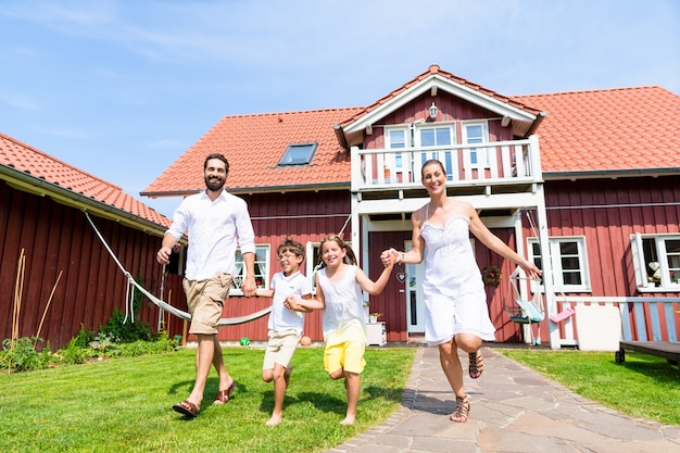 Photo happy family running on meadow in front of house on front yard grass