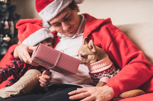 Happy family in Santa hat, father and child son giving Christmas gift at home