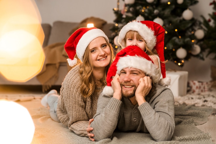 Photo happy family in santa hats lies on the floor in a christmas decorated room against the background of a christmas tree