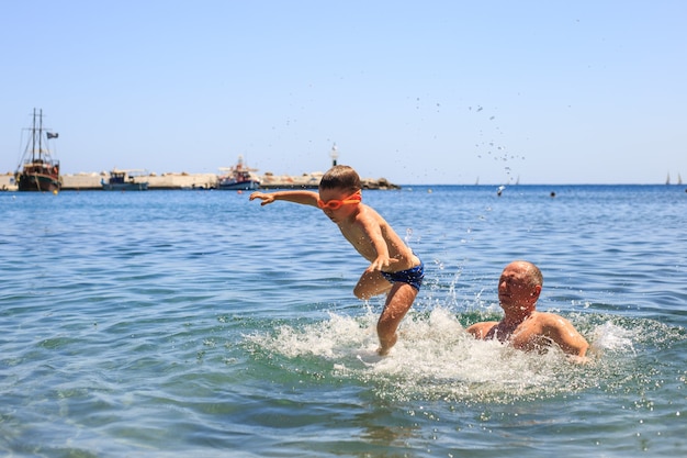 Счастливая семья на море весело и плещет воду летом