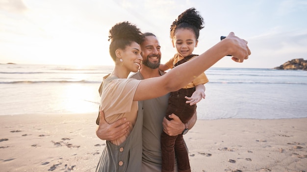 Happy family selfie and together on beach vacation or memory of tropical island holiday in Bali and bonding in summer Ocean sunset and parents with child in hug with love care and support