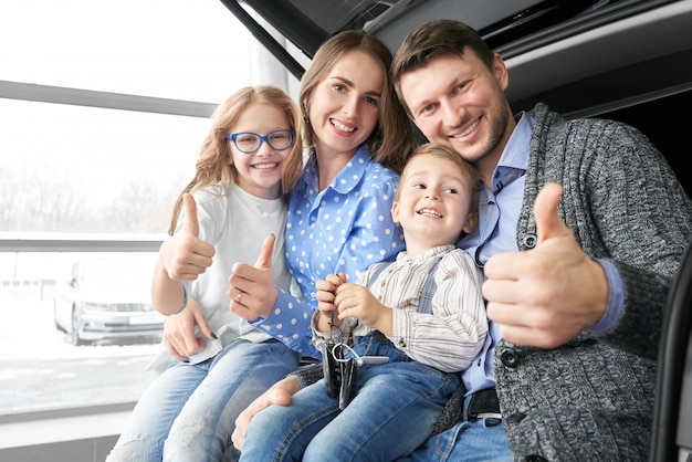 Happy family showing sign ok in auto salon