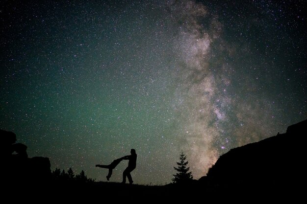 Happy family silhouette with Milky Way and beautiful night sky full of stars in background