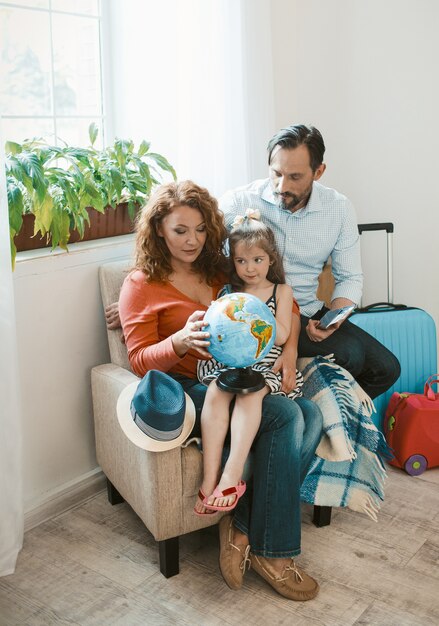 Famiglia felice che si siede alla poltrona che studia globo.