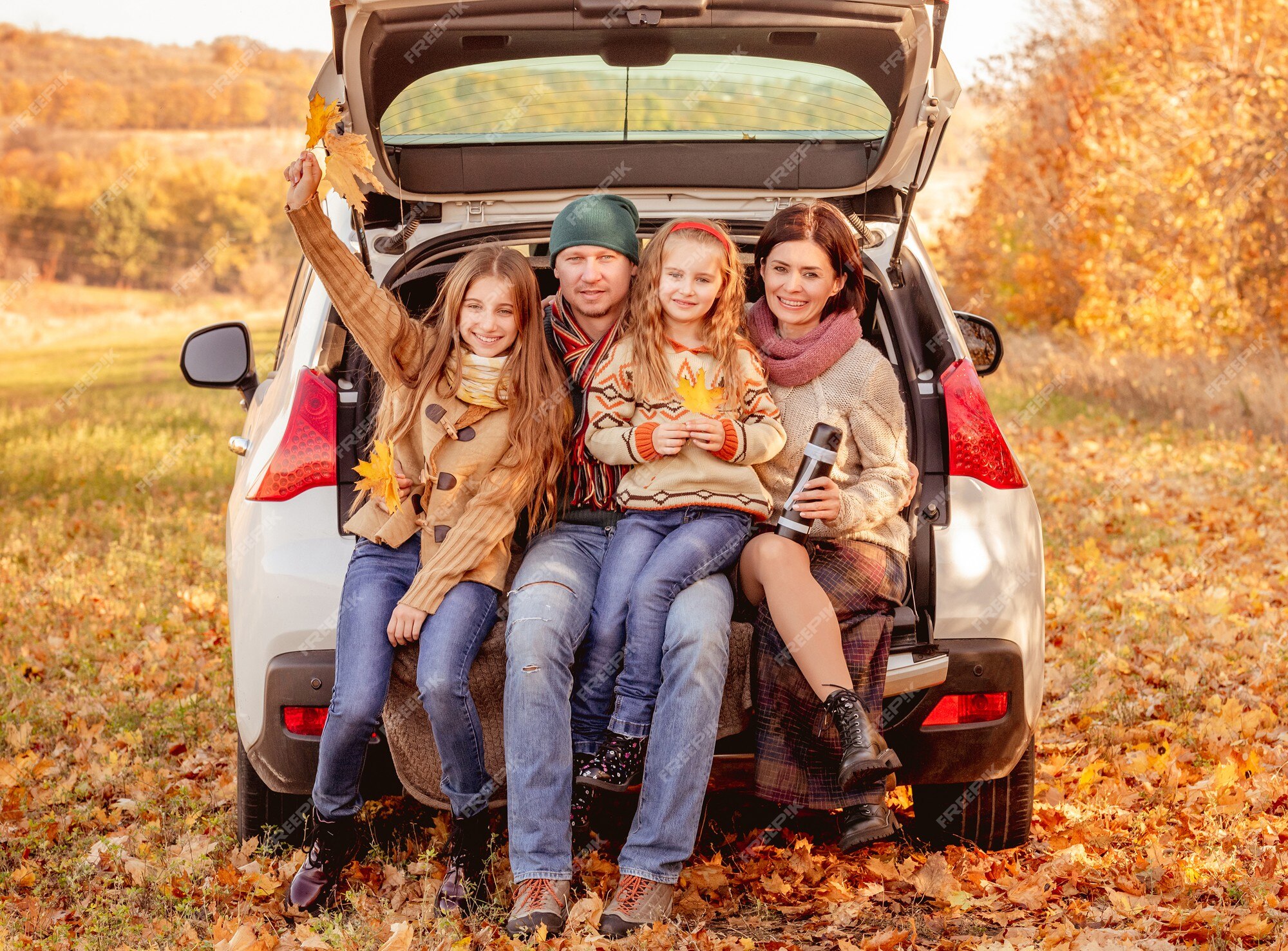 Premium Photo | Happy family sitting in car trunk on autumn background