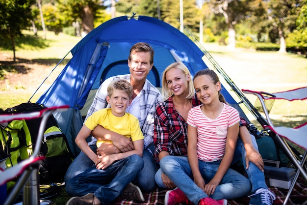 Photo happy family sitting in front of a tent