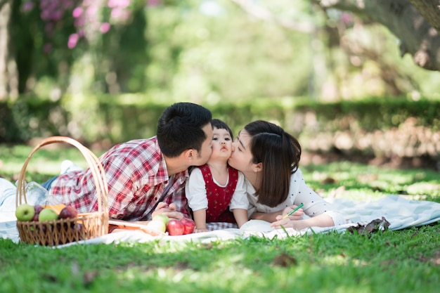 Happy family sitting on the grass during a picnic in a park