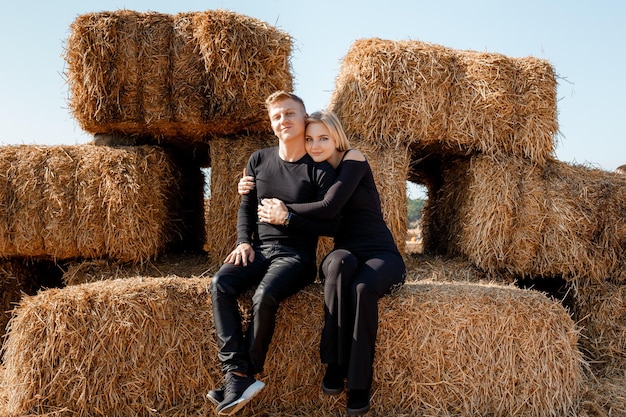 Happy family sitting on hay bales. outdoor market. Autumn time.