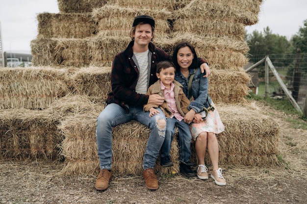 Happy family sitting on hay in countryside