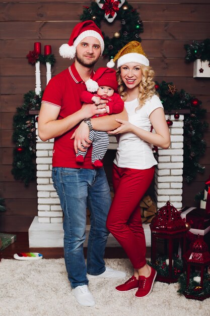 Happy family sitting near fireplace with little son and cute dog and smiling