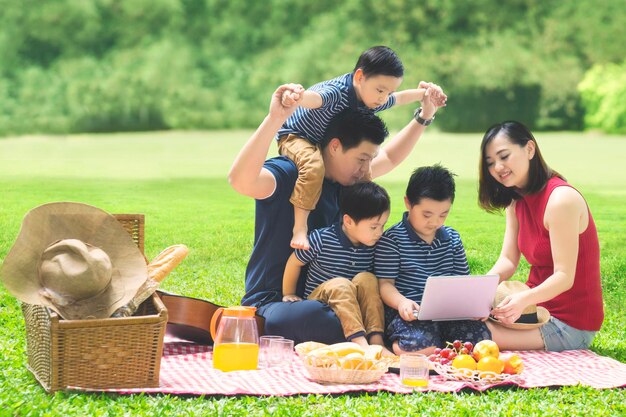 写真 公共の公園でピクニック用の毛布に座っている幸せな家族