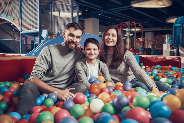 Happy family sitting in pool with balls