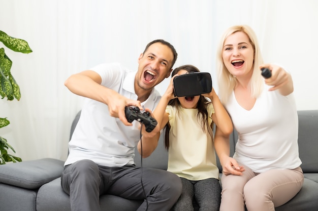 Happy family sitting on a sofa and playing video games.