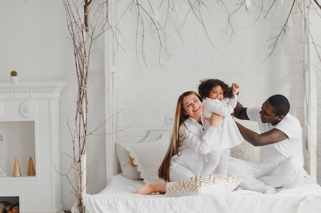 Happy family sitting in a white bed