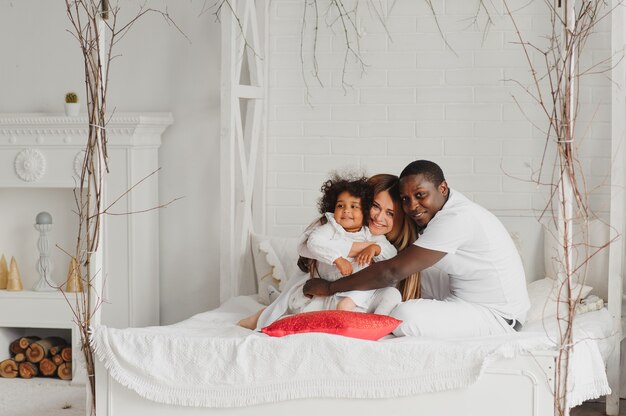 Happy family sitting in a white bed