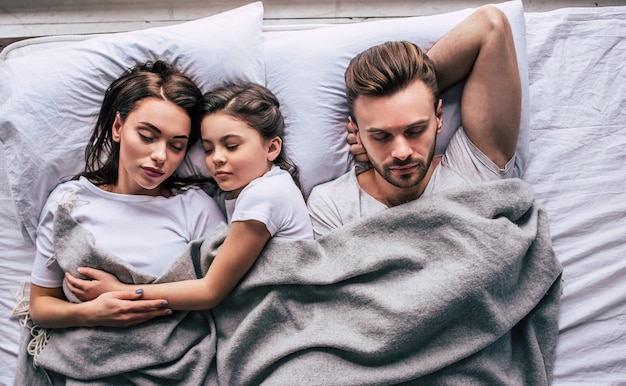 The happy family sleeping under the blanket