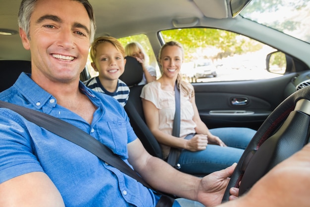 Happy family smiling at the camera in the car