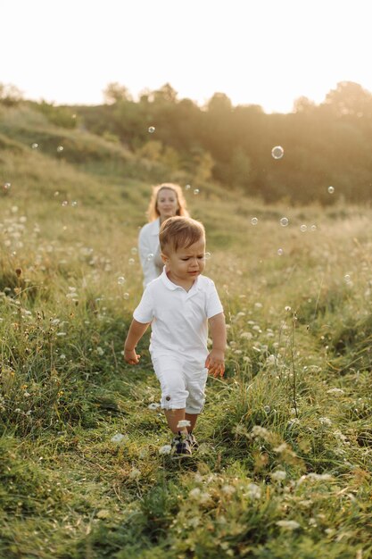 Happy family smiling and standing on the green grass in the\
field at sunset son with parents family weekend couple kissing