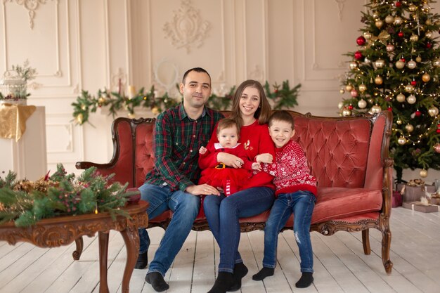 Happy family on sofa near Christmas tree.