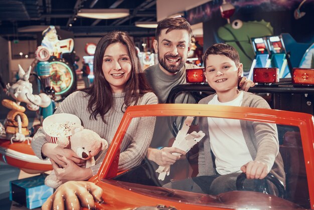 幸せな家族、息子のおもちゃの車に座っています。