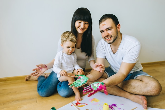 happy family son with parents painting a poster 