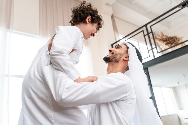 一緒に時間を過ごす幸せな家族。アラビア人の父と息子が家で遊んだり、さまざまな活動をしたりする