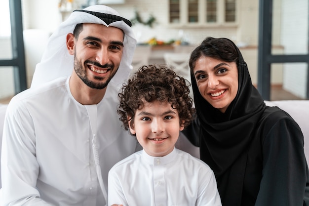 Famiglia felice che trascorre del tempo insieme. i genitori arabi e il loro figlio giocano e fanno diverse attività a casa